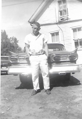 old photograph of man standing in front of an old car